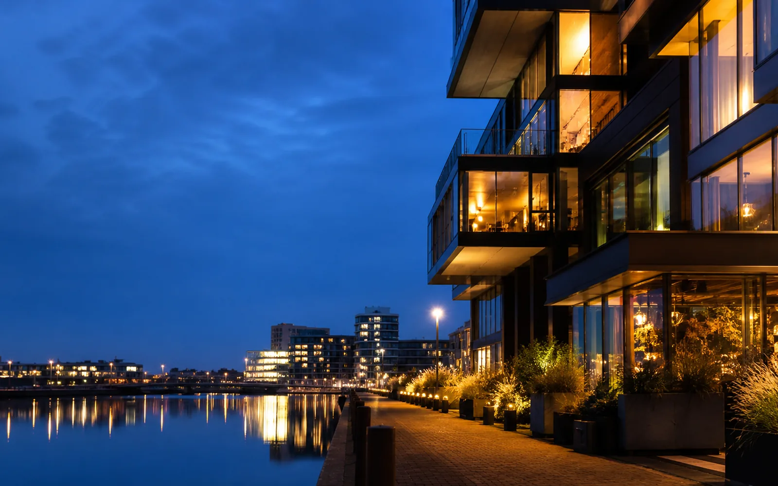Redactioneel avondbeeld van modern Amsterdam-West met warm verlichte architectuur